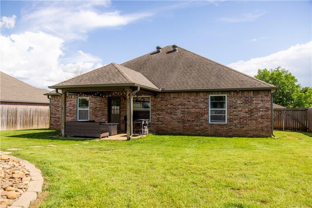 rear view of property featuring roof with shingles, brick siding, and a patio