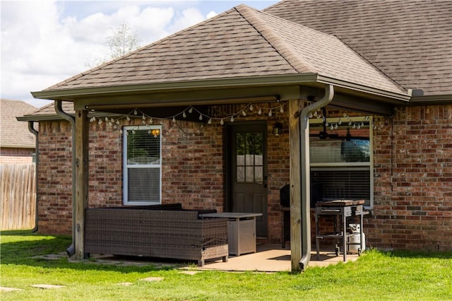 rear view of property featuring roof with shingles, a patio area, brick siding, and an outdoor living space