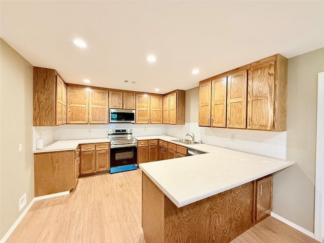 10098 Bayview Rd, Dardanelle, AR 72834 - kitchen with stainless steel appliances, a sink, brown cabinetry, a peninsula, and light wood-style flooring