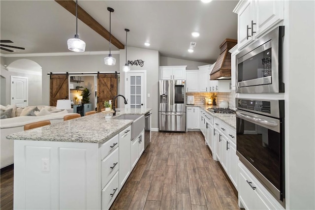 1904 Tull Dr, Pea Ridge, AR 72751 - kitchen with stainless steel appliances, a sink, premium range hood, open floor plan, and a barn door