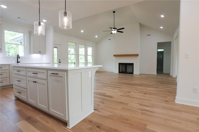 3 Berkshire Dr, Bella Vista, AR 72714 - kitchen featuring ceiling fan, light countertops, a fireplace, light wood-type flooring, and a kitchen island