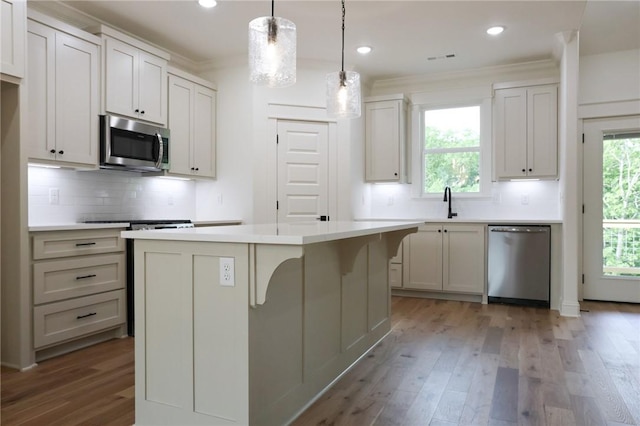 3 Berkshire Dr, Bella Vista, AR 72714 - kitchen with stainless steel appliances, a kitchen island, light wood-style flooring, tasteful backsplash, and ornamental molding