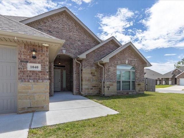 view of front of home with a front yard, brick siding, and stone siding