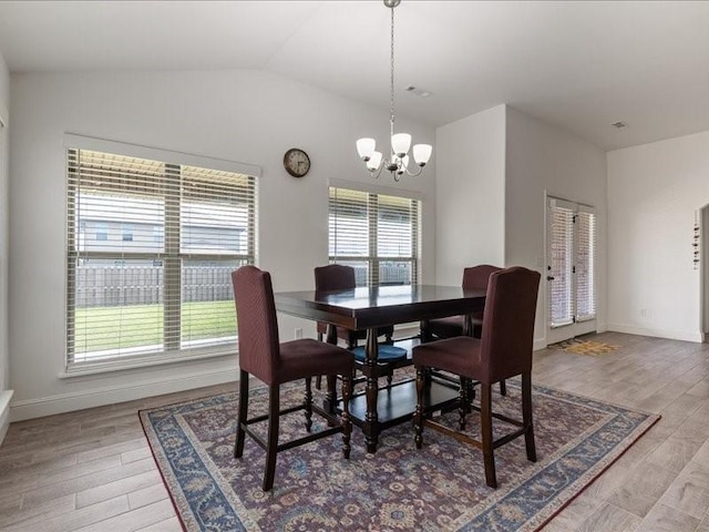 dining room with a chandelier, light wood finished floors, lofted ceiling, and baseboards