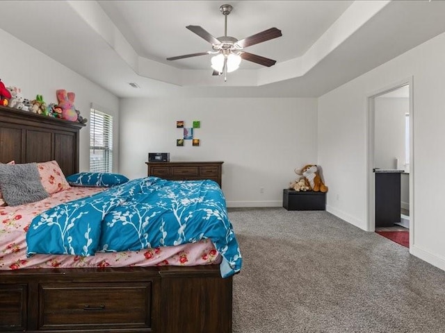 carpeted bedroom with a tray ceiling, baseboards, and a ceiling fan