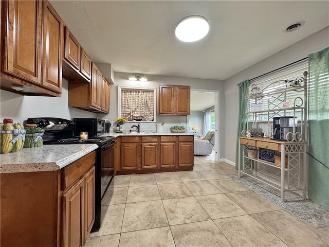 1008 E H St, Russellville, AR 72801 - kitchen featuring black appliances, brown cabinetry, a sink, light countertops, and light tile patterned floors
