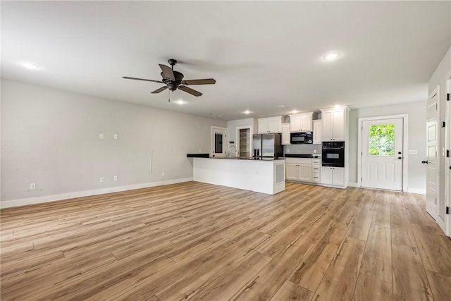 unfurnished living room featuring light wood-type flooring, baseboards, a ceiling fan, recessed lighting, and a sink