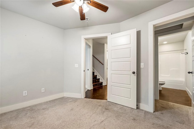 unfurnished bedroom with baseboards, carpet, ceiling fan, and ensuite bath