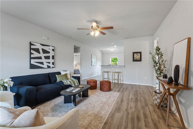 living area with wood finished floors, a ceiling fan, and baseboards