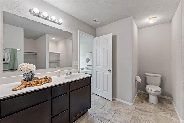 full bath with a textured ceiling, vanity, toilet, and tile patterned flooring