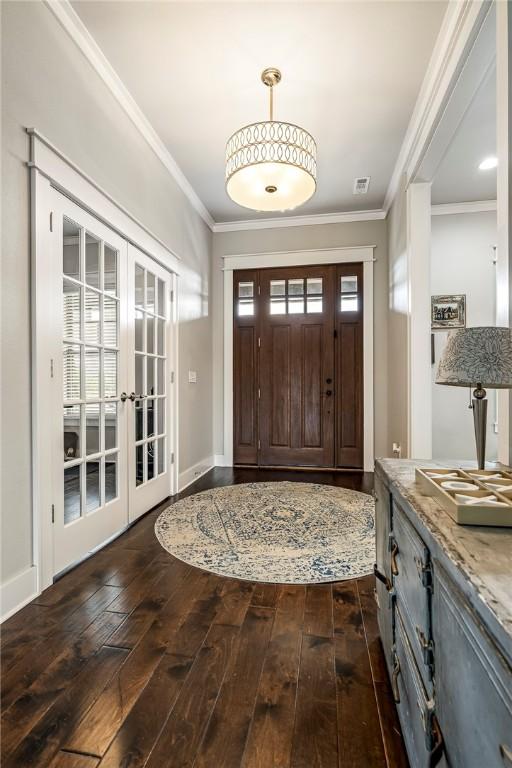 foyer entrance featuring french doors, dark wood-type flooring, and crown molding