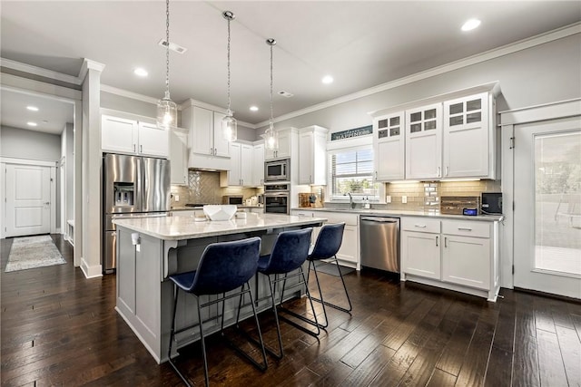 kitchen with appliances with stainless steel finishes, white cabinetry, a sink, a breakfast bar, and crown molding
