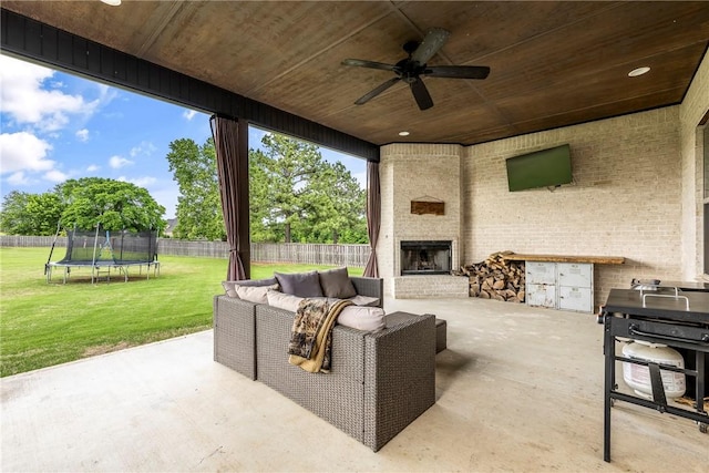 view of patio / terrace featuring a trampoline, ceiling fan, and an outdoor living space with a fireplace