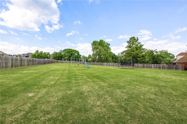 view of yard with a trampoline and a playground