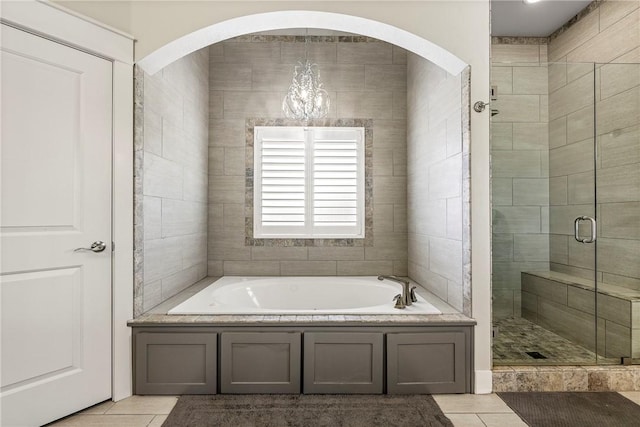 full bathroom with tile patterned flooring, a stall shower, a garden tub, and a chandelier
