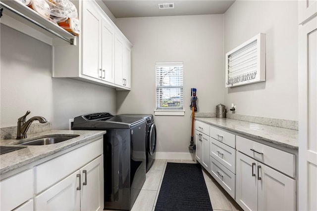 clothes washing area featuring separate washer and dryer, cabinet space, light tile patterned floors, and baseboards