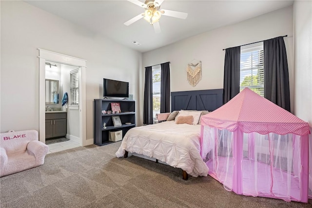 carpeted bedroom with multiple windows, ensuite bath, and a ceiling fan