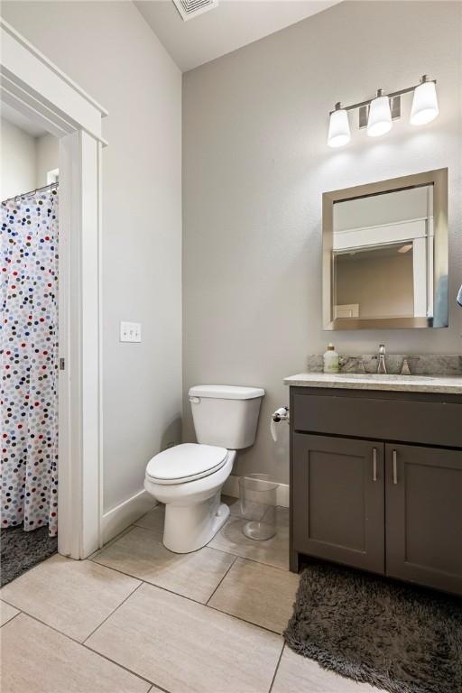 bathroom featuring toilet, vanity, tile patterned floors, baseboards, and a shower with shower curtain