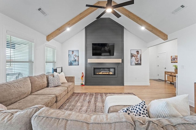 living area featuring beamed ceiling, baseboards, light wood-style flooring, a fireplace, and a ceiling fan