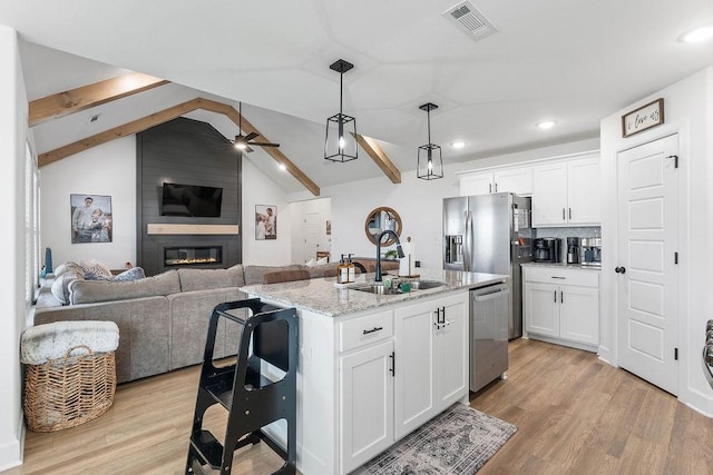 kitchen featuring a sink, appliances with stainless steel finishes, ceiling fan, open floor plan, and light wood-type flooring