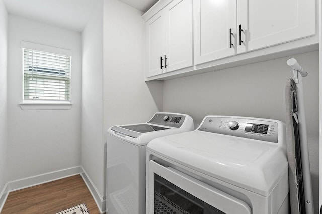laundry room featuring washer and clothes dryer, wood finished floors, cabinet space, and baseboards