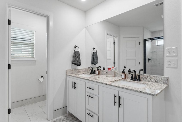 full bathroom with marble look tile flooring, a stall shower, double vanity, and baseboards