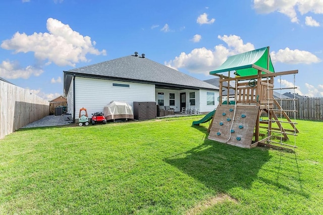 rear view of property featuring a playground and roof with shingles