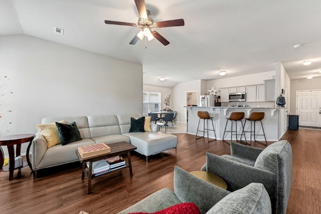 living room with ceiling fan, vaulted ceiling, and dark wood-style floors