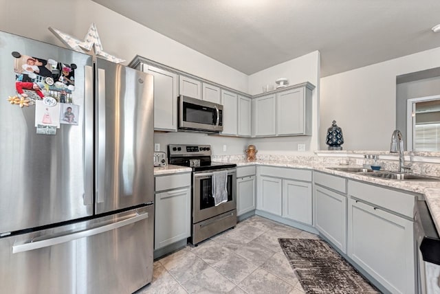 kitchen with stainless steel appliances, gray cabinets, and a sink