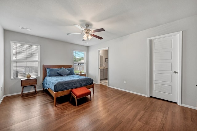 bedroom with wood finished floors, baseboards, a ceiling fan, and connected bathroom