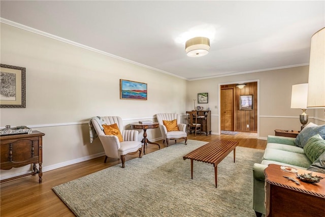 living room with wood finished floors, ornamental molding, and baseboards