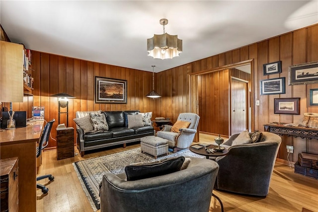 living room featuring a chandelier, light wood-style flooring, and wooden walls