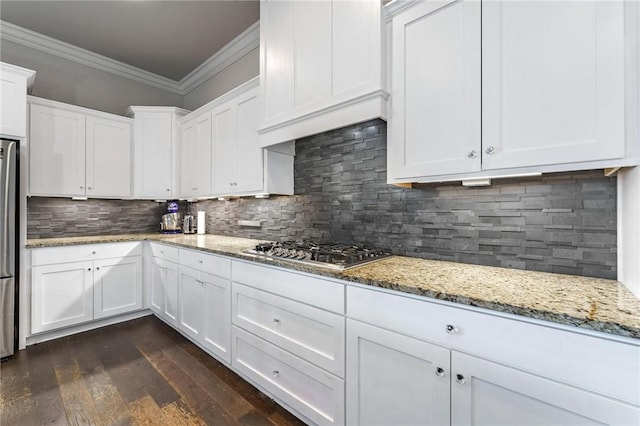 kitchen with stainless steel appliances, ornamental molding, white cabinets, tasteful backsplash, and light stone countertops