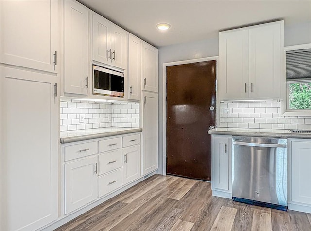 239 Mc 7043, Flippin, AR 72634 - kitchen featuring appliances with stainless steel finishes, light wood finished floors, decorative backsplash, and white cabinets