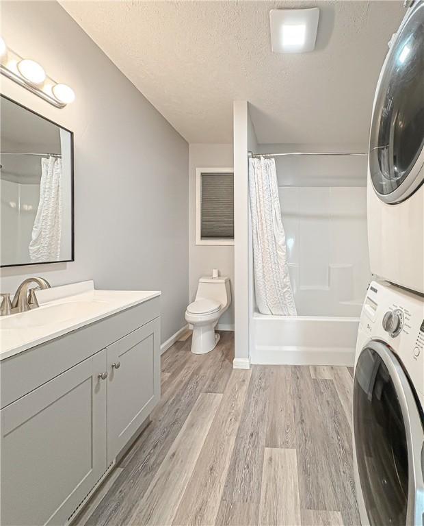 239 Mc 7043, Flippin, AR 72634 - bathroom with stacked washer and clothes dryer, a textured ceiling, toilet, wood finished floors, and vanity