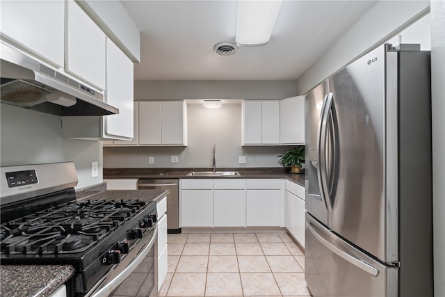 1207 SE E St, Bentonville, AR 72712 - kitchen with appliances with stainless steel finishes, a sink, under cabinet range hood, dark countertops, and white cabinetry