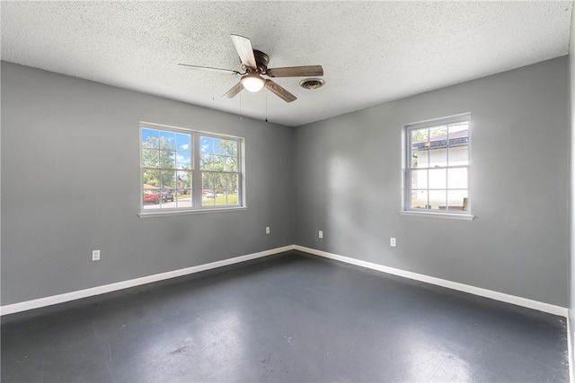 1207 SE E St, Bentonville, AR 72712 - empty room with plenty of natural light, a ceiling fan, concrete flooring, baseboards, and a textured ceiling
