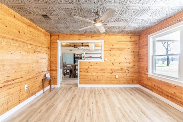 2193 Nevada 18 Rd, Prescott, AR 71857 - empty room with an ornate ceiling, ceiling fan, baseboards, wooden walls, and light wood-type flooring