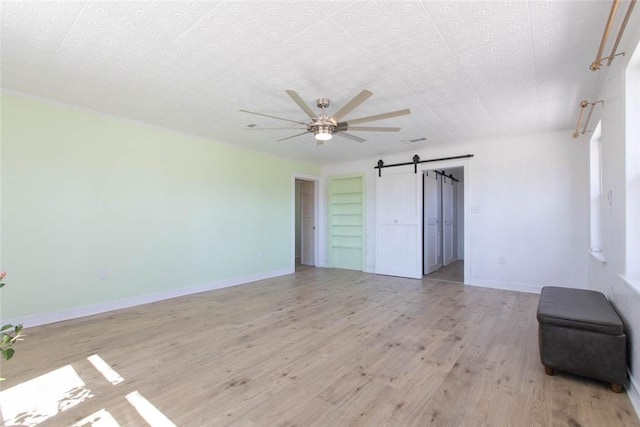2193 Nevada 18 Rd, Prescott, AR 71857 - unfurnished bedroom with a barn door, baseboards, light wood finished floors, and a ceiling fan