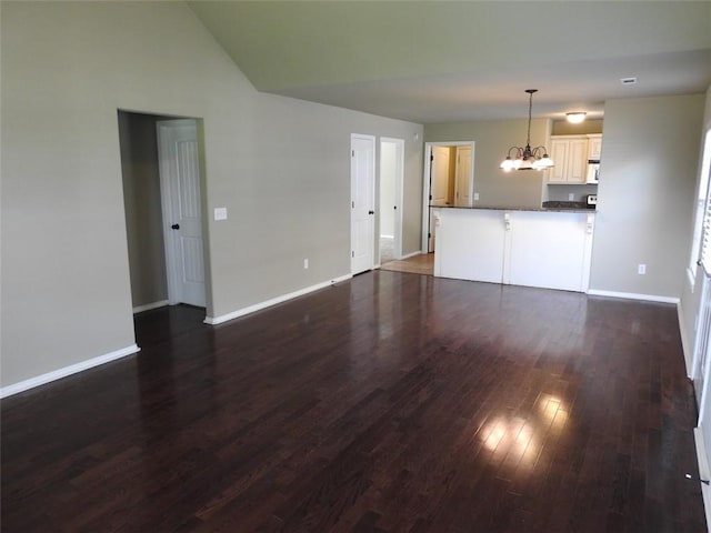 3804 Gibson Ave, Bentonville, AR 72712 - unfurnished living room featuring a chandelier, dark wood-type flooring, baseboards, and vaulted ceiling