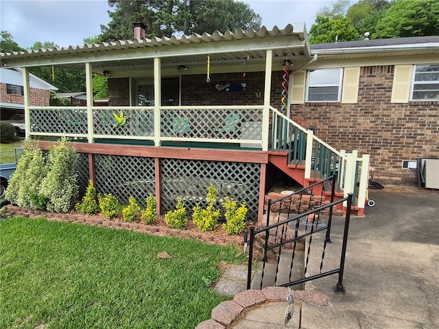 rear view of property featuring brick siding, covered porch, and a yard