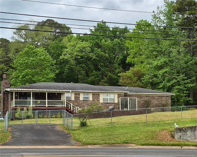 view of front of house featuring brick siding, a sunroom, asphalt driveway, and a chimney