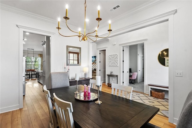 dining room featuring a chandelier, ornamental molding, light wood finished floors, baseboards, and stairway