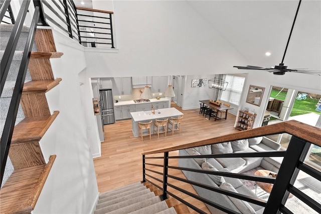 staircase featuring a towering ceiling, wood finished floors, recessed lighting, baseboards, and a chandelier