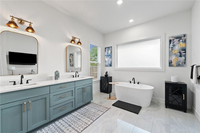 bathroom with double vanity, a freestanding bath, marble finish flooring, recessed lighting, and baseboards