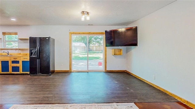 unfurnished dining area featuring dark wood-style floors, a sink, baseboards, and healthy amount of natural light