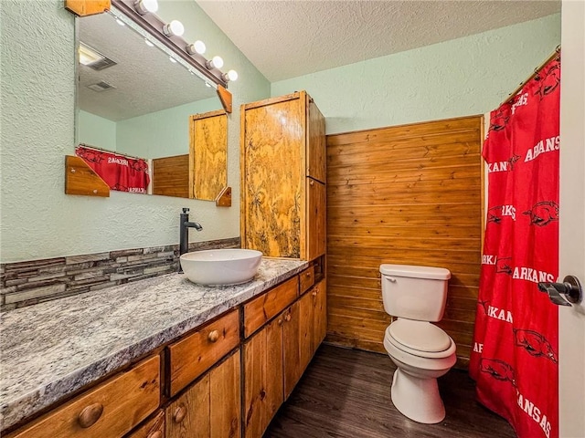 bathroom featuring a textured wall, a textured ceiling, wood finished floors, toilet, and vanity