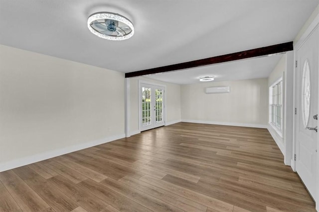21106 Kirksey Rd, Elkins, AR 72727 - unfurnished living room featuring beamed ceiling, wood finished floors, baseboards, and an AC wall unit