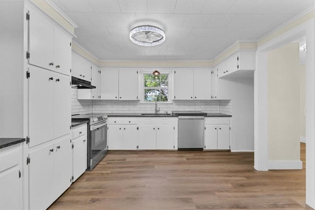 21106 Kirksey Rd, Elkins, AR 72727 - kitchen featuring appliances with stainless steel finishes, dark countertops, a sink, ornamental molding, and under cabinet range hood