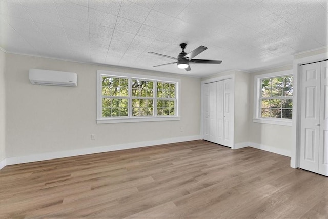 21106 Kirksey Rd, Elkins, AR 72727 - unfurnished bedroom featuring a wall mounted air conditioner, multiple closets, light wood-type flooring, baseboards, and crown molding